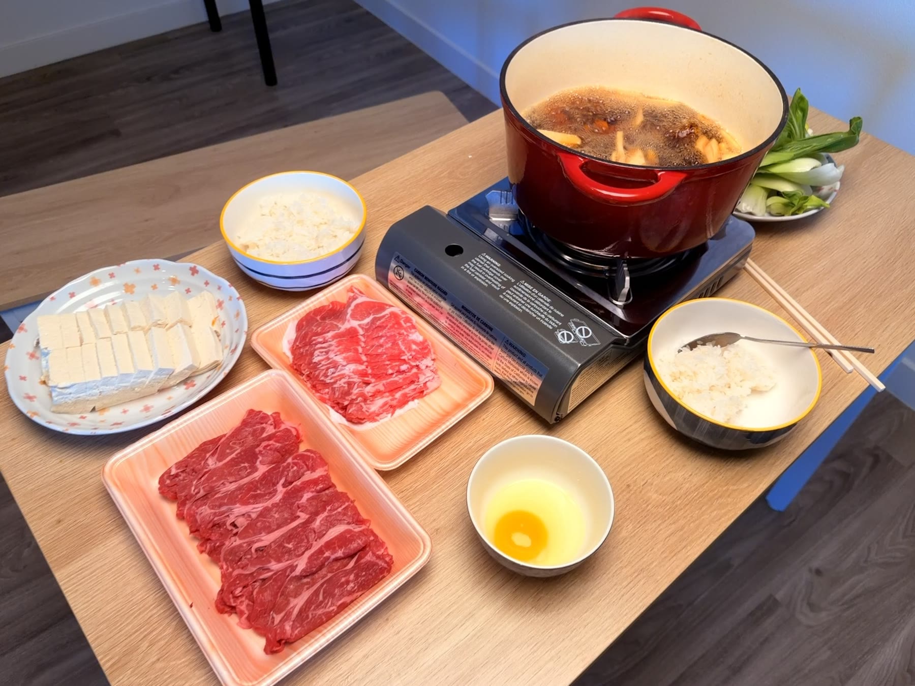 A home hot pot spread with beef, tofu, vegetables, and rice